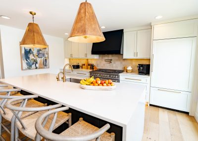 A modern kitchen featuring a sleek white countertop and a stainless steel sink, creating a clean and bright atmosphere.