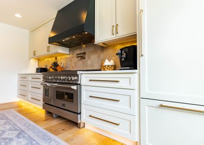 A sophisticated kitchen featuring a sleek stove, elegant sink, and a captivating painting adorning the wall.