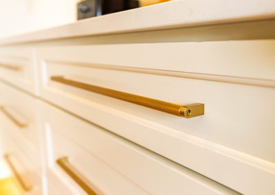 A detailed view of a white cabinet with lavish gold handles.
