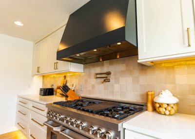 A sophisticated kitchen featuring a sleek stove, elegant sink, and a captivating painting adorning the wall.