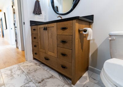 A clean bathroom featuring a toilet, sink, and a wooden cabinet, showcasing a simple and functional design.