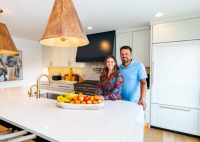 A man and woman are positioned in a bright kitchen, with a white island as the focal point of their interaction.