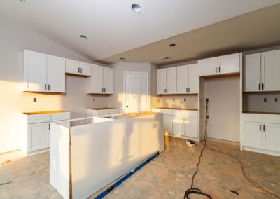 A kitchen undergoing remodeling, featuring new cabinets and an unfinished floor, showcasing construction progress.